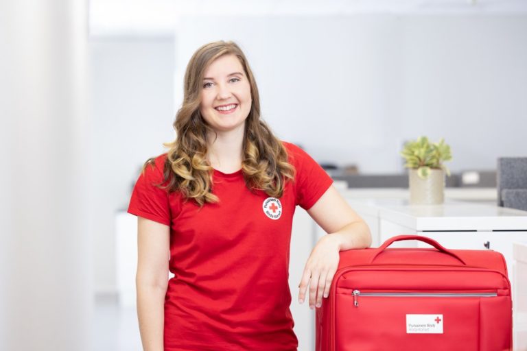 A first aid instructor stands with their suitcase of first aid training materials.
