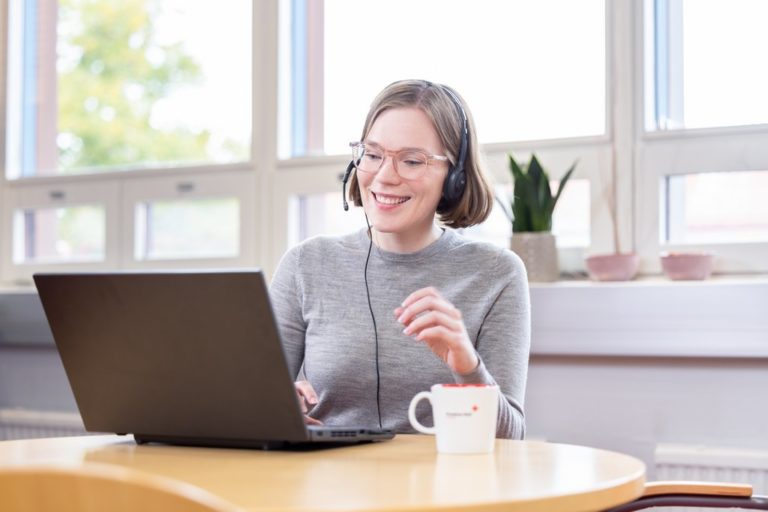 A woman sits at a table in a meeting with headphones on.