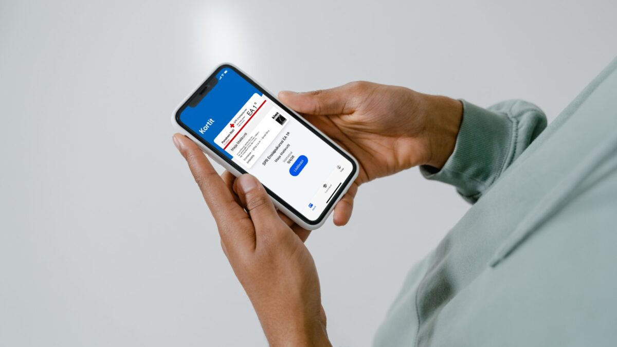 Henkilö pitää kädessään älypuhelinta, jossa on SPR ensiapukurssi EA1 pätevyystodistus näkyvissä. Henkilöstä näkyy vain kädet ja hieman vaaleanvihreää puseroa.